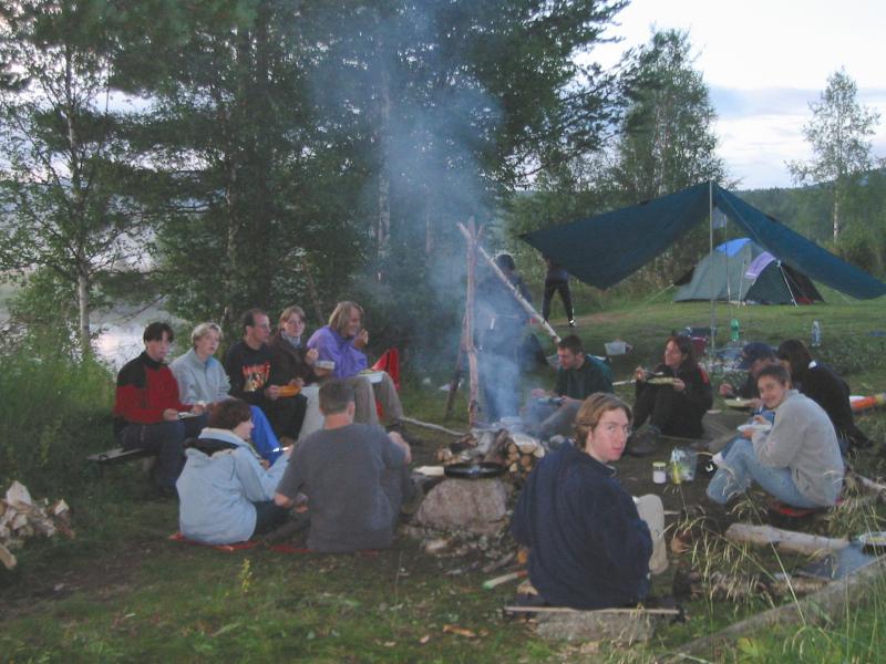 Die Norwegen Reisegruppe sitzt am rauchenden Lagerfeuer
